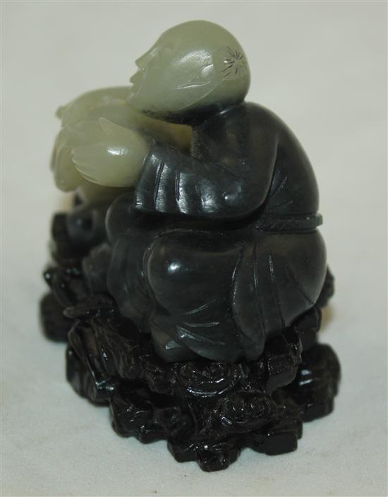 A Chinese pale celadon and dark grey jade and stand